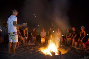 Attilio Celona e la sua classe di cajon intorno al fuoco, sul mare di ostia.jpg