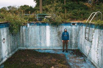 Caso, il suo k-way blu elettrico e una piscina.